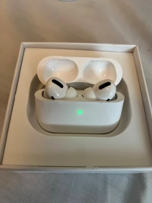 Apple AirPods Pro trådlösa hörlurar - Säljer ett par vita Apple AirPods Pro med laddningsetui. Hörlurarna har en stilren och kompakt design med silikonproppar och touchkontroller. Perfekta för dig som vill ha brusreducering och smidig anslutning till iPhone eller andra Apple-enheter.