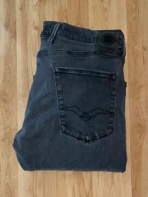 Replay hyperflex Anbass jeans  - Svarta Replay Hyperflex Anbass jeans med slim passform. Jeansen har stretchigt material för extra komfort och en snygg, mörk tvätt. OBS jeansen har hål vid skrevet och baktill på fickorna - se bild. Midja 40cm, längd 107cm. JAG SKICKAR EJ FLER BILDER NÄR JAG BÄR JEANSEN! för bättre inblick i passformen rekommenderar jag att googla på modellnamnet. För storleksguide kolla måtten noggrant då jeansen alltid kan vara uppsydda heller krympta och jag ej tar emot returer :) s5,2