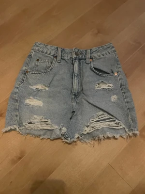 Ljusblå jeanskjol med slitna detaljer - Snygg ljusblå jeanskjol med slitna partier och fransig nederkant. Perfekt för en avslappnad och trendig look nu till sommaren.