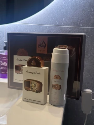 Lattafa Vintage Radio gift set - Fulla båda flaskorna. Endast testade. Förpackningen är elegant med detaljer i vitt, brunt och guld, vilket ger en lyxig känsla. Perfekt presentförpackning.