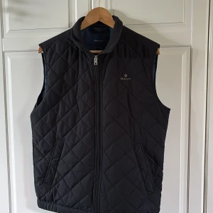Svart quiltad väst från GANT - Säljer den här supersnygga GANT västen perfekt nu för de varmare kvällarna. Köpt från deras hemsida ungefär ett år sedan men förtfarande i super skick. Inga hål eller fläckar. Pris kan diskuteras