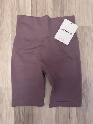 Lila shapewear shorts från Xshapes - Säljer ett par lila shapewear shorts från Xshapes med hög midja och scrunch-detalj bak. De är sömlösa och tillverkade i ett stretchigt material som formar och ger stöd. Perfekta under klänning eller kjol för en smickrande siluett.
