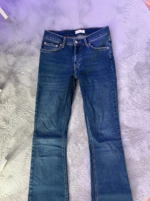 Blå bootcut jeans från Gina Tricot  - Säljer ett par klassiska blå bootcut jeans från Perfect Jeans. Jeansen har fem fickor, normal midja och snygga kontrastsömmar. Tillverkade i stretchigt denim för skön passform. Perfekta till en avslappnad och trendig look. Jag har sytt de lågmidjade själv därför kan de se lite konstigt ut när man inte har på sig de men ser bättre ut på enligt mig. 