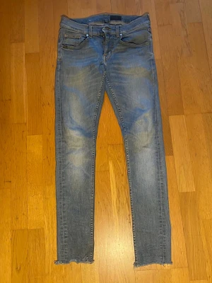 Tiger of Sweden Jeans  - Säljer ett par blå skinny Tiger of Sweden jeans med slitna detaljer och råa, avklippta benslut. Jeansen har klassisk femficksmodell och dragkedjegylf. Perfekta för en avslappnad och trendig look. Materialet är stretchigt denim för skön passform.