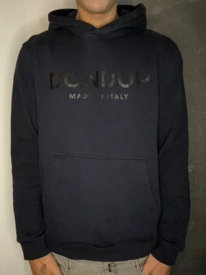 Marinblå hoodie från Dondup - Snygg svart hoodie från Dondup med diskret logga och texten 'MADE IN ITALY' på bröstet. Klassisk känguruficka framtill och mjukt material som känns skönt mot huden. Perfekt för en avslappnad och stilren look.