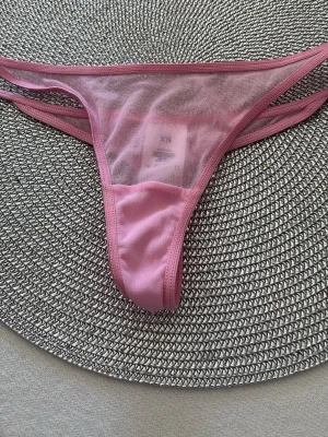 Rosa  stringtrosa St.Xs. - Säljer en rosa stringtrosa  i storlek XS. Trosan är med dubbla tunna sidoband och har en enkel, stilren design. Perfekt för dig som gillar en lätt och luftig känsla. Materialet är mjukt och följsamt.