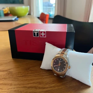 Elegant klocka från Tissot - Jag säljer denna fina klocka från tissot då jag inte använder den längre! Den har en svart urtavla och länken är i guld/silver. Nypris 5.295kr! 💗Jag skickar gärna fler bilder privat! Värdebevis finns. 