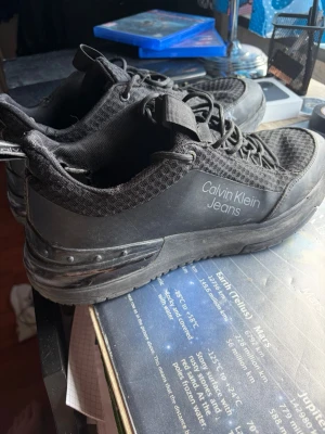 Svarta Calvin Klein Jeans sneakers - Snygga svarta sneakers från Calvin Klein Jeans med mesh- och syntetdetaljer. Skorna har en chunky sula, svarta skosnören och logga på sidan. Perfekta för dig som gillar en sportig och modern look.