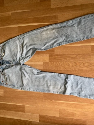 Ljusblå Levi's 501 jeans - Klassiska ljusblå Levi's 501 jeans med rak passform och fem fickor. Jeansen har knappgylf och den ikoniska läderpatchen bak i midjan. Tillverkade i slitstark bomullsdenim och har en vintagekänsla som passar perfekt till en avslappnad stil.