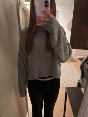 Grå stickad tröja från H&M - Mysig grå stickad tröja från H&M i storlek XS. Tröjan har en avslappnad passform, långa ärmar och ribbade muddar. Perfekt för lager på lager och enkel att matcha med olika outfits.
