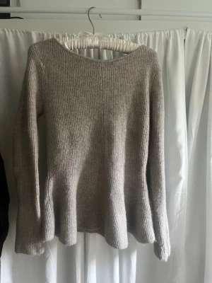 Beige ribbstickad tröja - Mysig beige stickad tröja med ribbstickat mönster och långa ärmar. Tröjan har en rund halsringning och lätt utsvängd passform nedtill.  Använd en gång 🥰