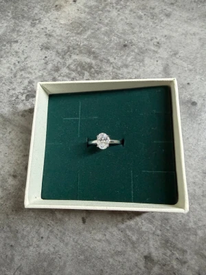 Silverring med stor klar sten Edblad - Snygg silverfärgad ring med en stor, oval klar sten i mitten. Ringen har en enkel och stilren design som verkligen framhäver stenen. Perfekt för dig som gillar att sticka ut med dina accessoarer. Storlek 17