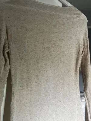 Beige Intimissimi långärmad topp - Intimissimi. En enkel och stilren beige långärmad topp i mjukt material. Toppen har en rak passform och är perfekt att matcha med olika outfits. Inga synliga detaljer eller mönster, bara clean och basic vibe.