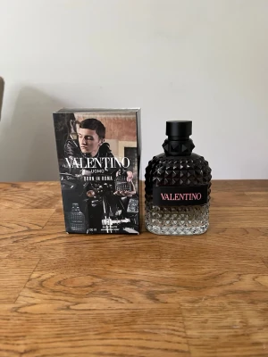 Valentino Uomo Born In Roma parfym - Valentino Uomo Born In Roma är en lyxig herrparfym i en stilren glasflaska med nitar och svart lock. Flaskan har en cool gradient från svart till transparent och etiketten är svart med rosa text. Förpackningen är svart med rosa detaljer och modern design. Ungefär 95/100 ml kvar👌🏽 