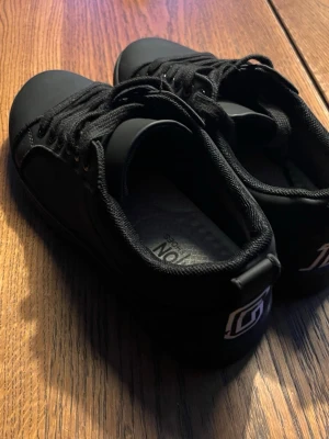 Loubutin oanvända  - Snygga svarta sneakers från loubutin med lågt skaft och klassisk design. Skorna har svarta snören, diskret logga på hälen och röd detalj på yttersulan och utbytt innesula. Tillverkade i ett matt syntetmaterial som ger en clean look.