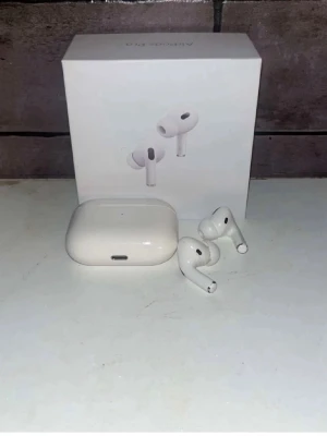 Apple AirPods Pro 2 1.1A usb c med fungeramde trans och anc - Säljer ett par vita Apple AirPods Pro 1.1 med trådlöst laddningsetui. Hörlurarna har en stilren och kompakt design i blank plast och levereras med förpackning samt laddningskabel. Perfekta för dig som vill ha brusreducering och grymt ljud i smidig form