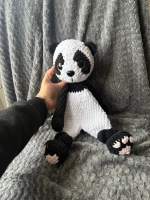 Stor virkad panda mjukisdjur - Säljer en handgjord virkad panda i svart och vitt med stora bruna ögon och rosa detaljer på tassarna. Pandan är mjuk och har en gosig textur, perfekt som dekoration eller kramkompis. 