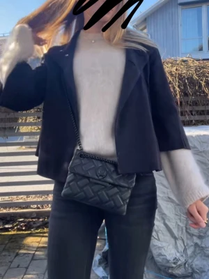 Svart quiltad handväska Kurt Geiger - Säljer en svart quiltad handväska från Kurt Geiger London med kedjerem och snyggt örndekor på locket. Väskan är i mjukt konstläder och har en kompakt, fyrkantig form som passar perfekt till alla outfits. Klassisk och trendig design med exklusiv känsla. Finns defekter som visar på användning, kom privat för fler bilder. Annars mycket fin och nypris ca 3000! 