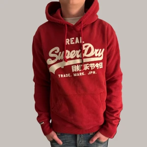 Superdry Hoodie - Röd superdry hoodie i storlek M. Toppen skick och skit snygg! Sitter som M och kanske snäppett större.