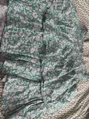 Grön blommig kortkjol med volang - Säljer en grön kortkjol med vita blommor och volangdetaljer. Kjolen har bred resår i midjan som gör den bekväm och enkel att bära. Perfekt för dig som gillar en avslappnad och trendig stil.