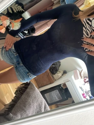 intimisemi Mörkblå tight långärmad topp - Snygg mörkblå långärmad topp i stretchigt och tunt material. Figurnära passform som framhäver siluetten och passar perfekt till jeans eller kjol. Enkel och stilren design utan tryck eller detaljer.