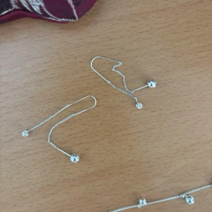 Silvriga örhängen med kedja och pärlor - Ett par stilrena silvriga örhängen med tunn kedja och små klara pärlor i ändarna. Örhängena har en minimalistisk design och passar perfekt för dig som gillar diskreta men snygga accessoarer🌸
