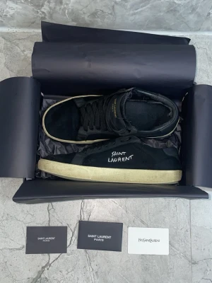 Svarta Saint Laurent sneakers - Hej, säljer dessa jätte snygga Saint Laurent skor i storlek 42. Skorna ska vara slitna, modellen är så☺️ Skorna är använda Bara under som är lite sönder men inget man ser eller märker vid användning. Rekommenderar dessa starkt ! Perfekt för sommaren🌟 priset kan självklart Diskuteras.  Skriv vid frågor eller bilder 🤝 OBS bara skor medföljer vid köp 😊✌️
