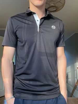 Puma Golf Pikétröja – Svart – Strl M - Säljer en stilren Puma golfpiké i svart med vit detalj vid knäppningen. Funktionsmaterial som andas och transporterar bort fukt, perfekt för golf, träning eller vardagsbruk.  • Märke: Puma Golf • Storlek: M • Färg: Svart med vit detalj • Skick: Mycket fint skick • Lätt och bekvämt funktionsmaterial • Passar både på golfbanan och till vardags  Pris: 149 kr