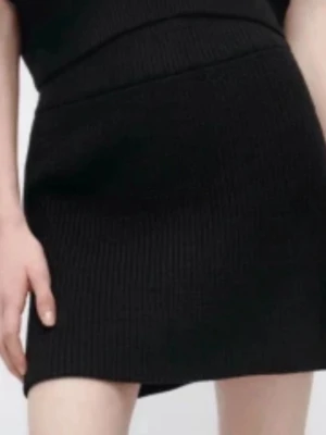 Svart ribbad stickad kortkjol - En svart, ribbad stickad kortkjol med enkel och stilren design. Kjolen har en rak passform och är perfekt för att skapa en trendig look. Passar till många olika outfits och är lätt att matcha.