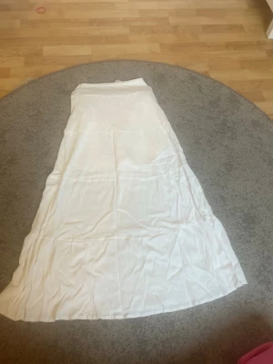 Vit långkjol från Gina tricot  - Säljer en enkel och flowy vit långkjol i mjukt bomullstyg. Kjolen har en lätt utsvängd form och är perfekt för dig som gillar en clean och avslappnad stil. Den är även väldigt stretchig. Passar till många olika outfits och är riktigt bekväm💓aldrig använd💓