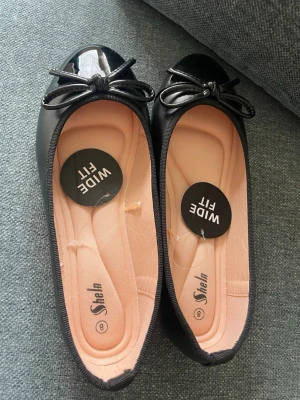 Svarta ballerinaskor med rosett Shein - Svarta ballerinaskor från Shein med bred passform (wide fit). Bekväma och stilrena med rosett framtill. Perfekta till vardag🌸                    Storlek 38-39 (märkt 8, men upplevs lite stora  för mig )
