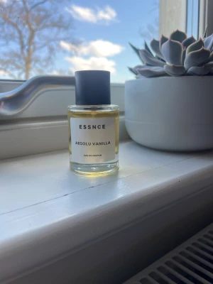 ESSNCE Absolu Vanilla Eau de Parfum - ESSNCE Absolu Vanilla Eau de Parfum med en transparent glasflaska och svart cylinderformad kork. Parfymen har en ljusgul nyans och minimalistisk etikett. Doften är vaniljbaserad och flaskan är stilren och modern, perfekt för dig som gillar söta och mjuka dofter. Hör av er om ni har frågor!💕