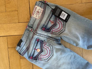 True Religion ljusblå jeans med kontrastsömmar - Säljer ett par ljusblå jeans från True Religion. Köpt fel storlek, alla lapparna finns kvar. Nypris 2300