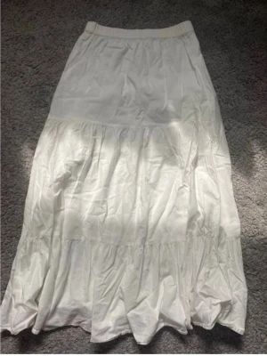 Vit lång kjol - Jätte fin kjol i fint skick, en liten röd fläck längst ner på baksidan av kjolen. Därav priset. Kan skicka bild på den privat om det behövs! Storlek 158. Nypris 349kr