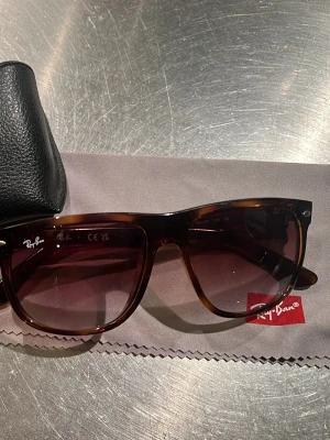 Boyfriend solglasögon Ray-Ban - Snygga solglasögon från Ray-Ban i klassisk Boyfriend-modell. Bågarna är bruna i sjölpadsfärgare och glasen är tonade i mörkbrunt. Kommer med originalfodral och putsduk. Perfekta för soliga dagar och ger en tidlös vibe. Riktigt bra skick!!!