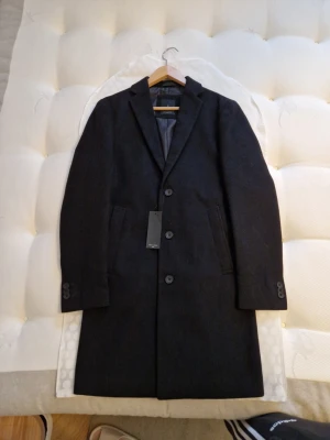 Oanvänd Herr Kappa/Rock  - Stilren svart kappa har slät insida. Perfekt för en snygg och tidlös look. Storlek XS Sista pris 400 kr. Inga byten eller returer. Skickar spårbart mot porto. 