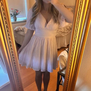 Bow dress - Gina Tricot - Supersöt ljusrosa kortklänning med puffärmar, v-ringning och stor rosett i ryggen. Klänningen har omlottkänsla och är gjord i ett tunt, luftigt tyg som ger en flowy look. Perfekt för sommarens alla tillfällen och ger en romantisk vibe.