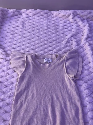 Beige stickad klänning med volangärm - Supersöt beige stickad klänning från Newbie med volangärmar och rund hals. Perfekt för dig som gillar en enkel men gullig stil. Materialet är mjukt och bekvämt, och klänningen har en rak passform.