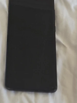 Samsung Galaxy S20 med två skal - Säljer en svart Samsung Galaxy S20 med två snygga mobilskal. Ett transparent skal från Guess med guldigt logomönster och ett beige Nillkin Super Frosted Shield. Perfekt för dig som vill ha både stil och skydd till mobilen.