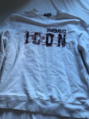 Vit sweatshirt från Dsquared2 ICON - Vit sweatshirt från Dsquared2 med trycket 'ICON' i svart och rött framtill. Tröjan har rund halsringning, långa ärmar och ribbade muddar. Perfekt för dig som gillar streetwear och vill ha en statement-piece i garderoben. den moststår strl s den har inga skador eller något sånt öppen för byten och prisförslag 