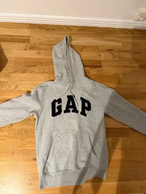 Populär GAP grå hoodie!  - Säljer en grå hoodie från GAP med stor svart logga på bröstet. 