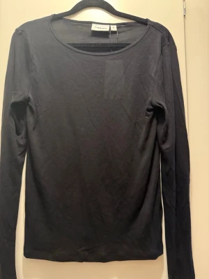 Svart långärmad genomskinlig topp från kappahl - En enkel och stilren svart långärmad topp från Kappahl. Toppen har rund halsringning och är gjord i ett tunt, mjukt material som känns skönt mot huden. Perfekt att styla lager på lager eller bära som den är.