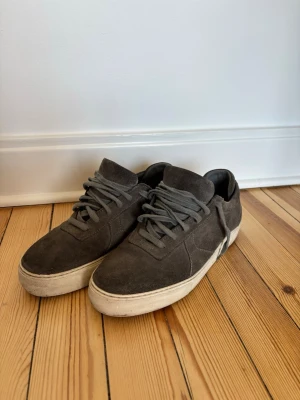 Mörkgråa Axel Arigato sneakers i mocka - Säljer mina Axel arigato skor som inte kommit till användning. Använda men i gott skick. 