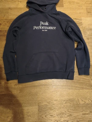Blå Peak Performance Hoodie Strl S/M - Säljer en riktig fin blå Peak Performance hoodie som är i storlek M men passar mig som har storlek S.
