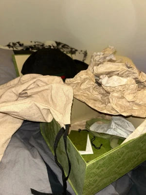 Svart keps från Gucci med röd-grön rand - Säljer en svart keps från Gucci med den klassiska röd-gröna randen på sidan. Kepsen har böjd skärm och justerbar rem bak. Materialet är bomull och kepsen kommer med originalkartong och tags. Perfekt för dig som vill ha en stilren och lyxig accessoar. Kvitto finns plus påse, box, Gucci kort, storlek L 59cm