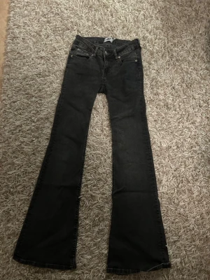 Svarta bootcut jeans från 157 - Bootcut jeans i svart denim från 157 med klassisk femficksdesign och låg midja. Modellen heter Bell och har vida ben som ger en snygg siluett. Perfekta för dig som gillar retrostil och vill ha ett par jeans som sticker ut. Aldrig andvänd