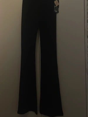 Svarta bootcut leggings - Säljer ett par svarta leggings med bootcut-modell och hög midja. De är stretchiga och bekväma, perfekta till en snygg och avslappnad look. Materialet känns mjukt och följsamt. Passar dig som gillar trendiga och stilrena byxor.