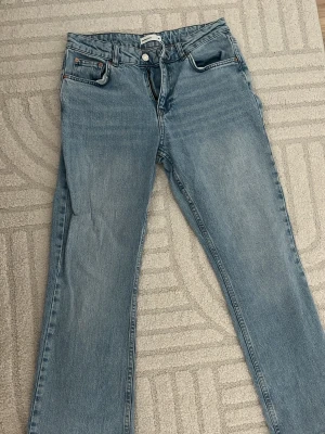 Ljusblå Flared jeans från Gina tricot - Säljer ett par ljusblå jeans från Gina tricot med flared passform . Jeansen har låg/normal midja, gylf med dragkedja och knapp samt diskreta kontrastsömmar. Perfekta för en avslappnad och trendig look.