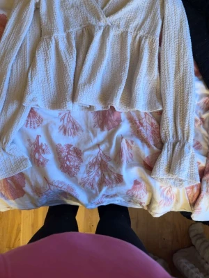 Beige omlottopp från Gina Tricot - Säljer en beige omlottopp från Gina Tricot i strukturerad bomullsmix. Toppen har långa ärmar med lätt volang vid ärmslut och en avslappnad passform. Perfekt att styla med jeans eller kjol för en trendig look.