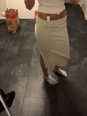 Beige midikjol från ONLY - Säljer en beige midilång kjol från ONLY. Kjolen har en rak passform med slits på sidan och är tillverkad i ett mjukt, ribbat material.